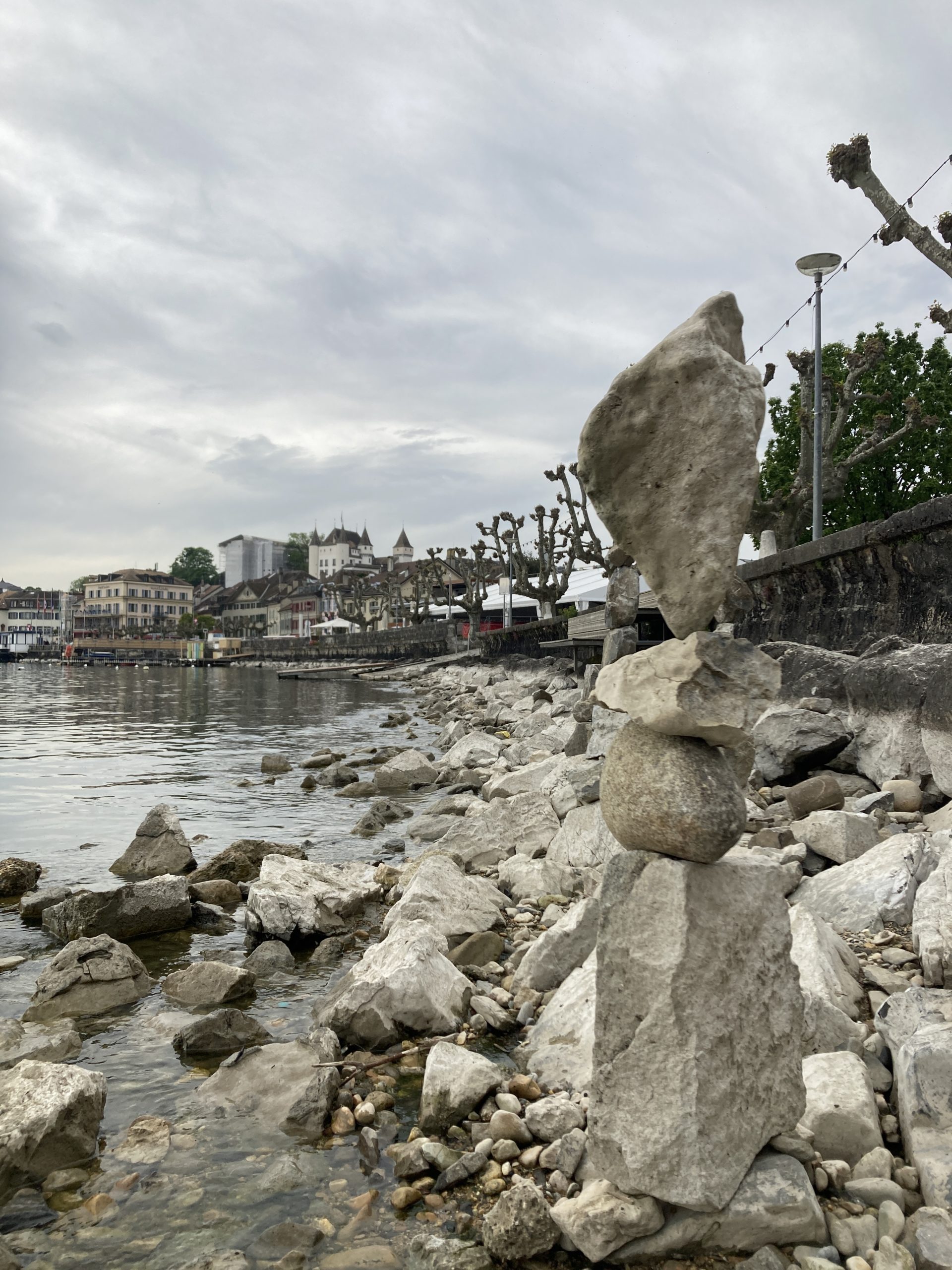 Balanced stones at the lake side with a view of the castle of Nyon