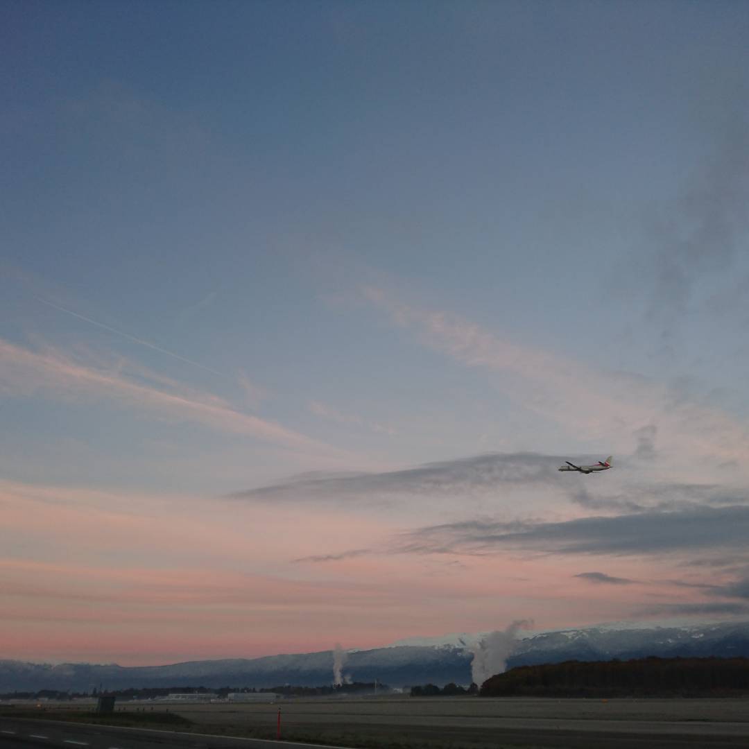 Goodbye Geneva. A plane flies away from the sunrise.