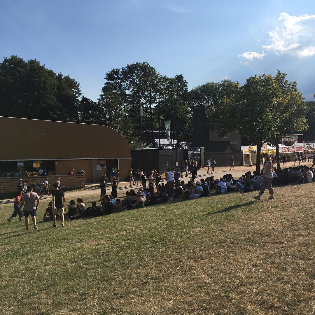 Heat adverse humans shelter from the sun waiting for a group to start playing on the big stage.