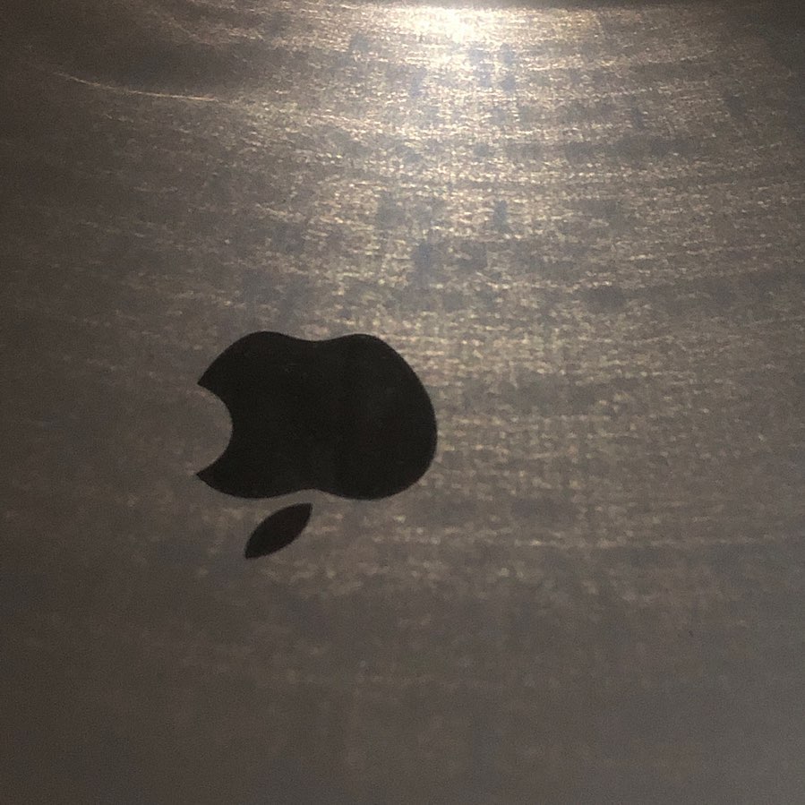 Apple logo with light reflected from a can onto a Mac book pro top case.
